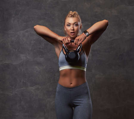 Beautifull fitness woman in gray sportswear doing exercise with dumbbells in the fitness center.の写真素材