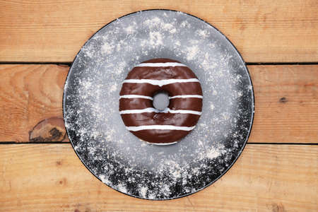 Appetizing chocolate donut with sprinkles lie on a wooden boards.の写真素材