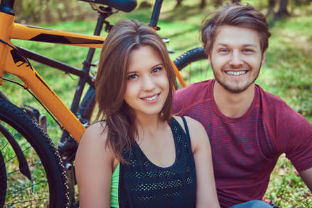 Group of young friends hiking through the forest with bikes on a beautiful summer dayの写真素材