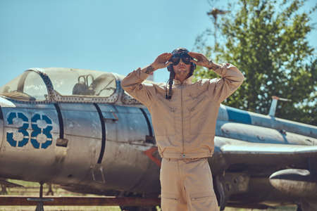 Pilot in uniform and flying helmet standing near an old war fighter-interceptor.の写真素材