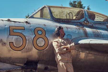 Pilot in uniform and flying helmet standing near an old war fighter-interceptor.の写真素材
