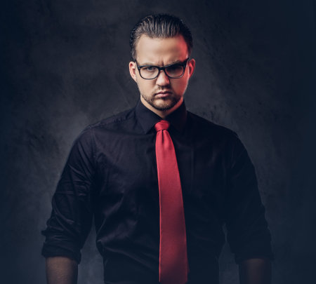 Portrait of a brilliant villain in a black shirt with a red tie.