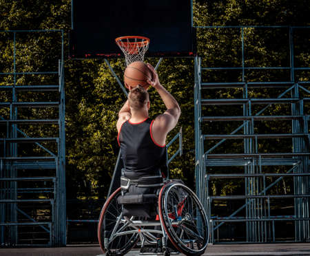 Cripple basketball player in a wheelchair plays on open gaming ground.の写真素材