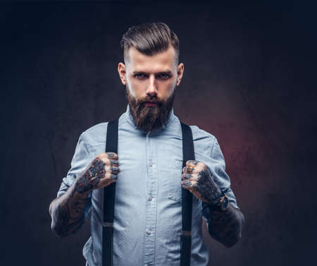 Portrait of a handsome old-fashioned hipster in a blue shirt and suspenders.の写真素材