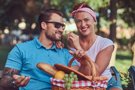 Attractive middle age couple during dating, enjoying a picnic on a bench in the city park.の写真素材