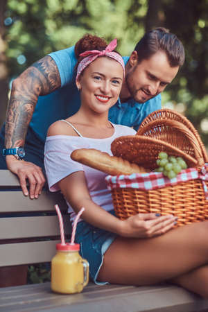 Attractive middle age couple during dating, enjoying a picnic on a bench in the city park.の写真素材