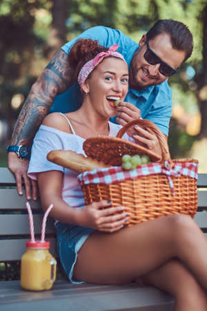 Attractive middle age couple during dating, enjoying a picnic on a bench in the city park.の写真素材