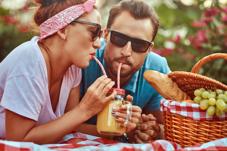 Portrait of a happy middle age couple during romantic dating outdoors, enjoying a picnic while lying...