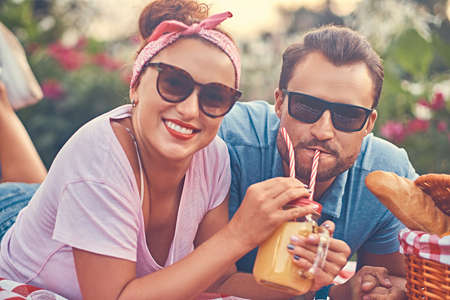 Portrait of a happy middle age couple during romantic dating outdoors, enjoying a picnic while lying...