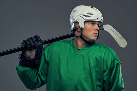 Professional hockey player in full equipment with gaming stick on shoulders against a gray background.の写真素材