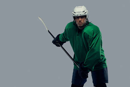 Professional hockey player trains in full equipment with gaming stick against a gray background.の写真素材