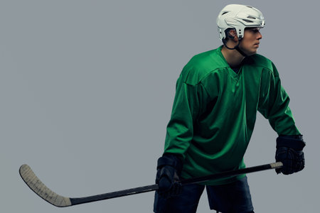 Professional hockey player trains in full equipment with gaming stick against a gray background.の写真素材