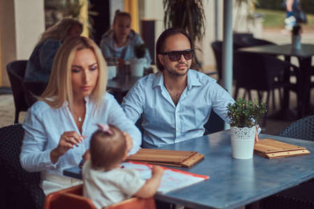 Family and people concept - happy mother, father and the little girl in outdoor cafe.の写真素材