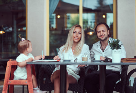 Family and people concept - happy mother, father and the little girl in outdoor cafe.の写真素材
