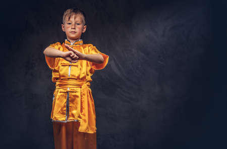 Cute boy dressed in the traditional costume of a Tibetan monk shows the tricks from the wellness complex at the studio.の写真素材