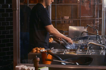 Cook is stirring vegetables in a wok. Cooking process in an Asian restaurant.
