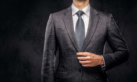 Cropped portrait of a successful businessman buttoning his elegant suit. Isolated on a dark background.の写真素材