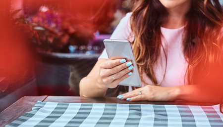 Portrait of a middle age businesswoman with long brown hair using a smartphone while sitting at the outdoor cafe.の写真素材