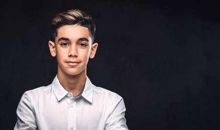 Handsome young guy dressed in white shirt standing with crossed arms. Isolated on the dark background.の写真素材