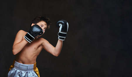 Handsome shirtless young boxer during boxing exercises, focused on process with serious concentrated...