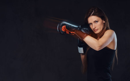 Beautiful brunette female boxer during boxing exercises, focused on a process with serious...
