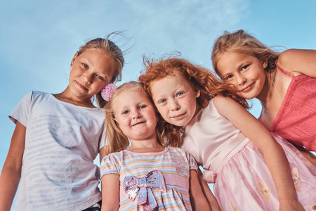 Low angle portrait of happy cute little friends against the sky background.の写真素材