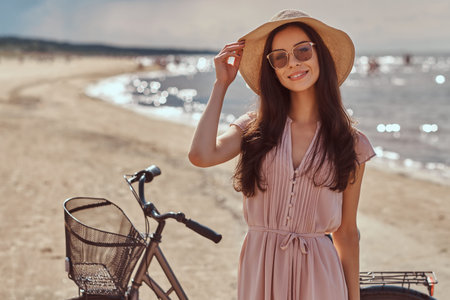 Portrait of a smiling beautiful brunette girl with long hair in sunglasses and sunglasses wearing a...