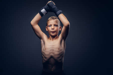 Young shirtless boy boxer wearing sports gloves posing in a studio.の写真素材