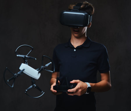 Young teenager dressed in a black t-shirt wears virtual reality glasses and controls the quadcopter...