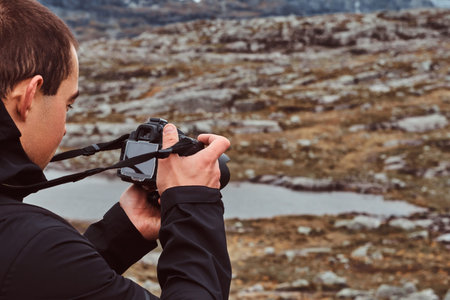 Nature photographer tourist with camera shoots while standing on the mountain.
