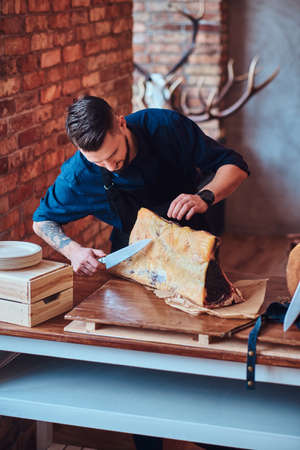 Chef cook cutting exclusive jerky meat on table in a kitchen with loft interior.の写真素材