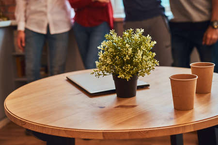 Close-up photo of a laptop, two paper cups and flower on a table in student dormitory.の写真素材