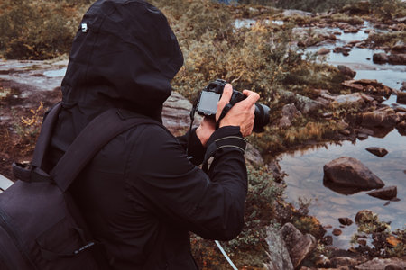 Nature photographer tourist with camera shoots while standing on the mountain.