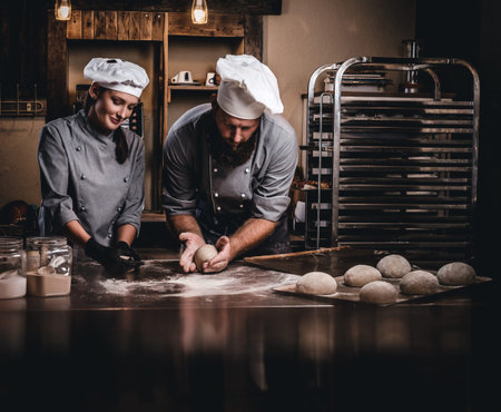 Chef teaching his assistant to bake the bread in a bakery.