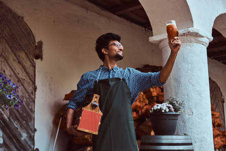 Expert brewer in apron standing outdoors checking the quality of brewed drink at brewery factory.の写真素材