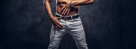 Cropped photo of a sporty man with muscular body in jeans posing in studio.の写真素材