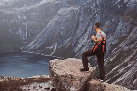 Tourist stands on the peak of the mountain with an amazing view of the Norwegian fjord.の写真素材
