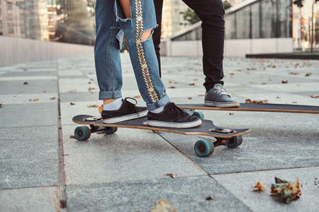Leisure and sport concept - close-up photo of a trendy dressed teen couple with skateboards on street.の写真素材