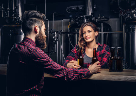 Bearded male and his girlfriend enjoying craft beer during dating at indie brewery.の写真素材