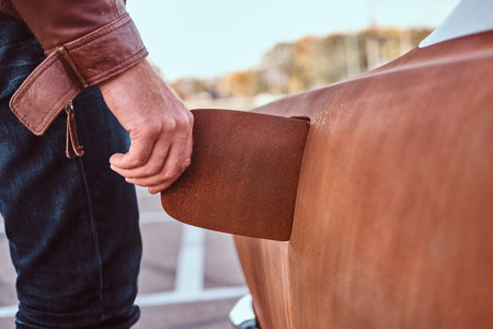 Male hand opens the gas cap of a tuned retro car for refueling.の写真素材