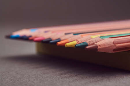 Multicolored pencils lying on a yellow notepad.