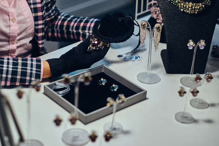 Close-up photo of a jewelry worker presenting a costly necklace with gemstones in a luxury jewelry store.の写真素材