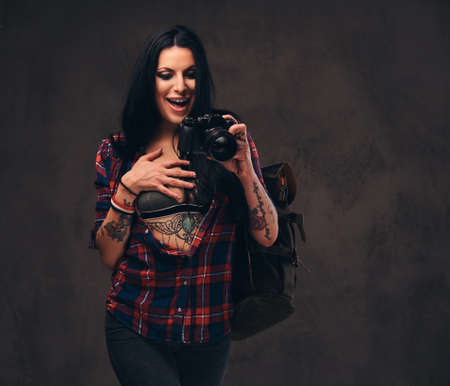 Seductive tattooed hipster girl wearing a red unbuttoned checked shirt posing a camera.の写真素材