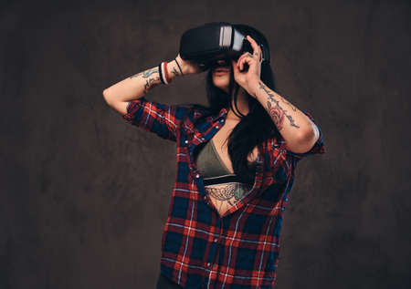 Tattooed girl wearing a red unbuttoned checked shirt wearing a VR headset.