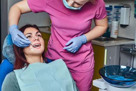 A young woman having examination while sitting in the dentists chair with opened mouth.の写真素材