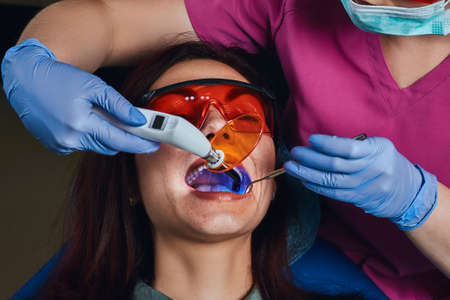 Female dentist treating a patient. A young woman sitting in the dentists chair.の写真素材