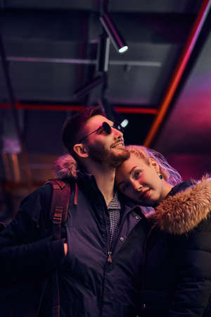 Attractive couple in love. A beautiful girl hugging her boyfriend standing in the night on the street.の写真素材