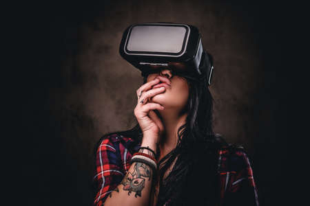 Tattooed girl wearing a red unbuttoned checked shirt wearing a VR headset.