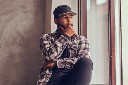 Pensive African-American bearded man looking out the window.