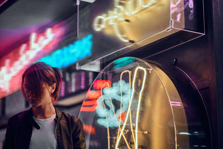 Stylish redhead girl standing in the night on the street. Illuminated signboards, neon, lights.の写真素材
